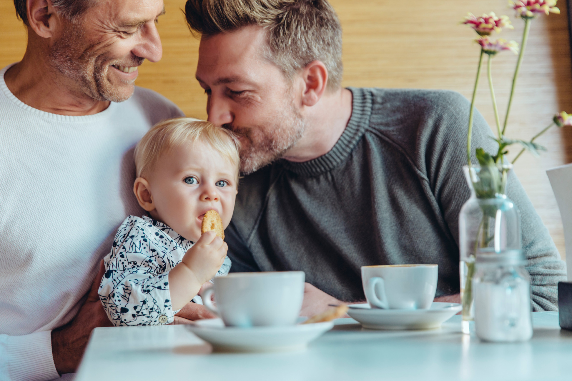 Same-sex parents cuddling their baby in cafe, Cologne, NRW, Germany