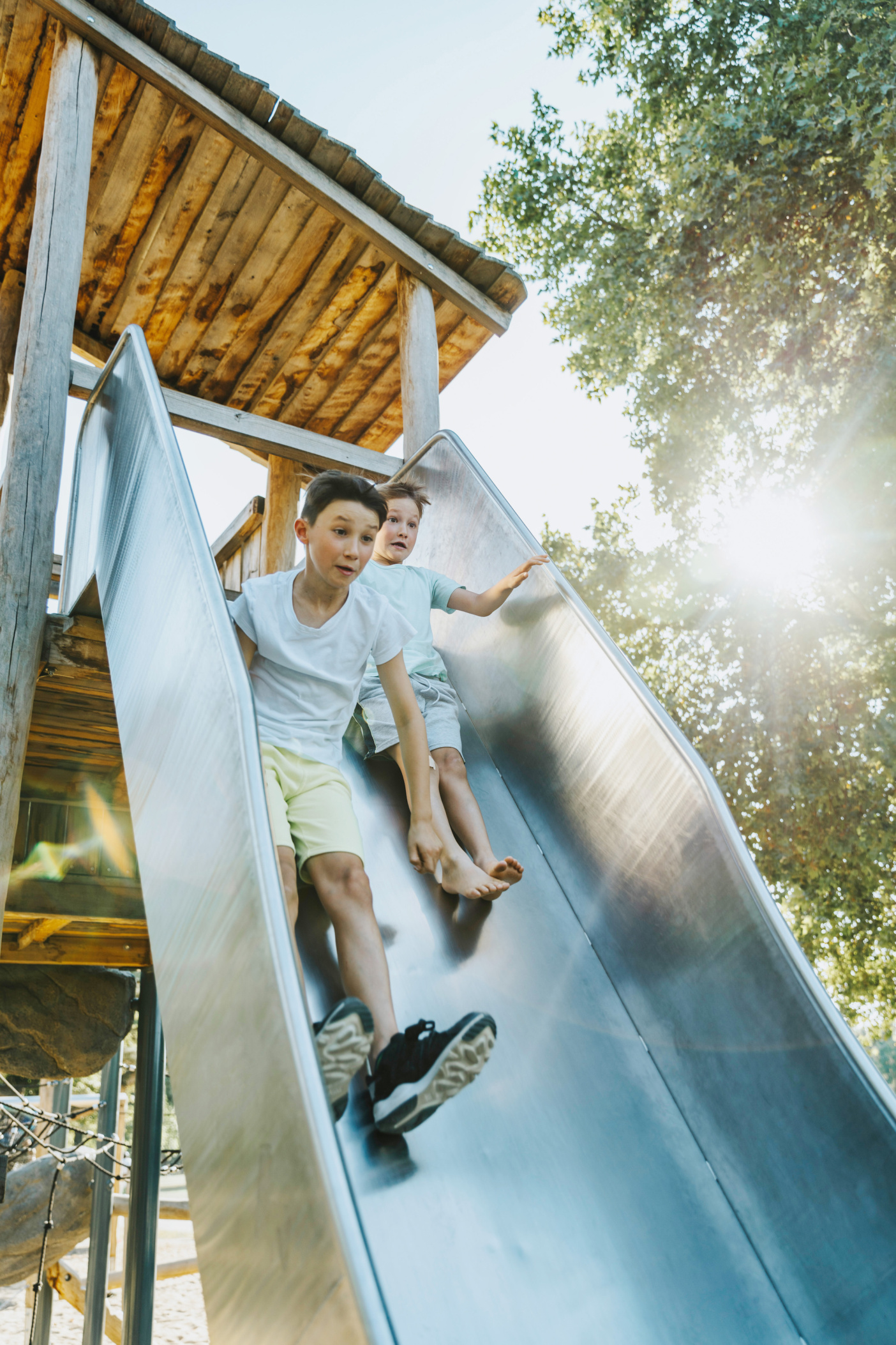 Boys using a steep slide on playground, Cologne, NRW, Germany