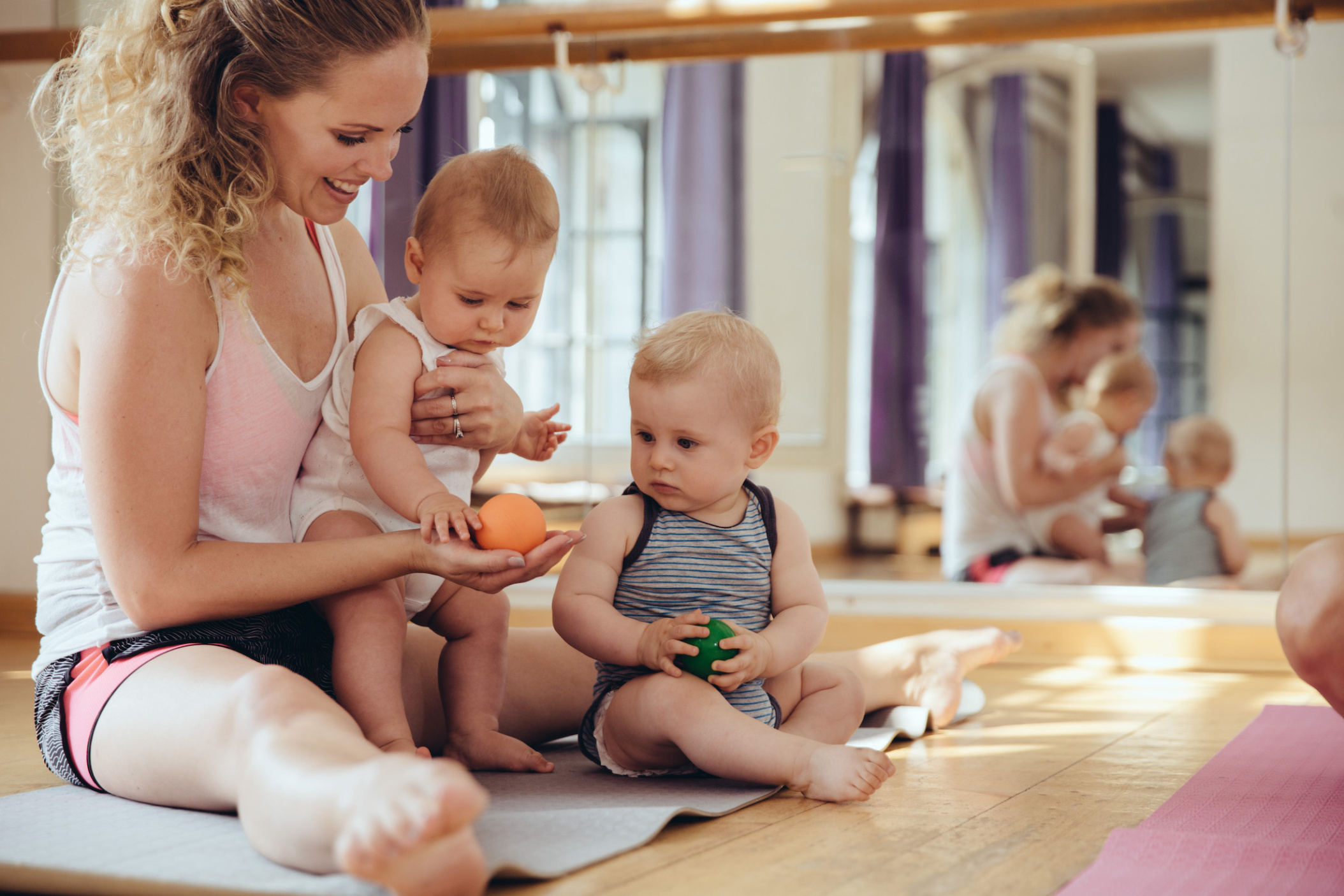 Mother with playing twin babies sitting on yoga mat, Cologne, NRW, Germany