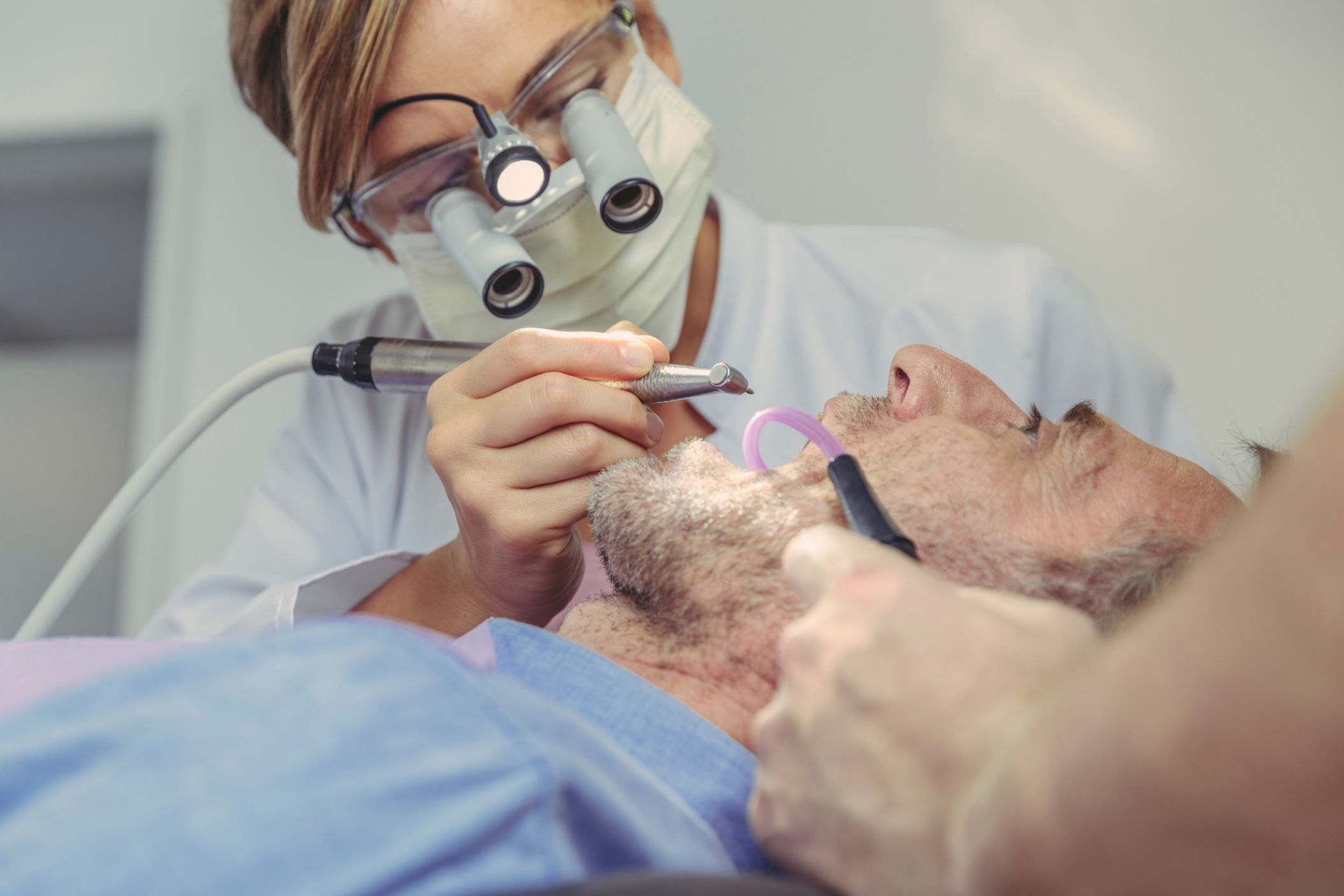 Dentist and using magnifying glasses while working on patient’s teeth, Germany
