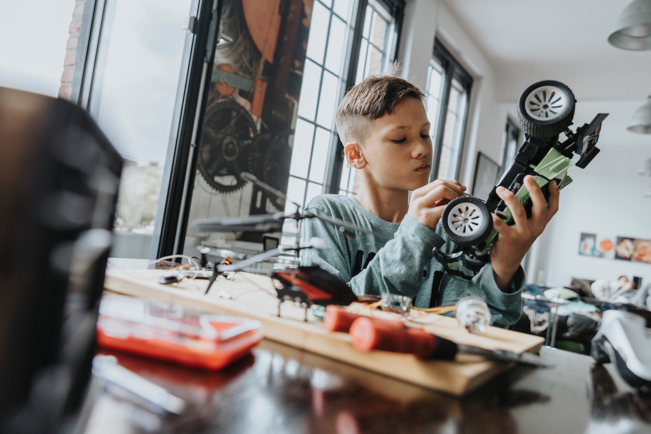 Boy tinkering on radio-controlled car with screwdriver and wires, Wuppertal, NRW, Germany