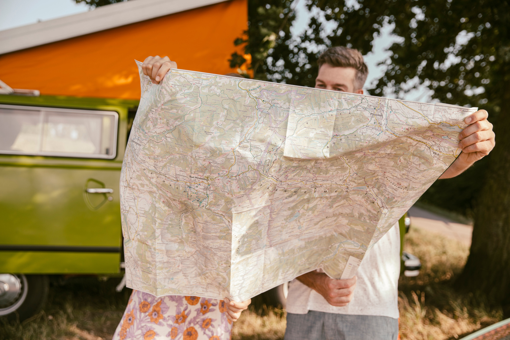 Couple looking at map in front of their T2 bus on a summer trip through North Rhine-Westfalia, Germany