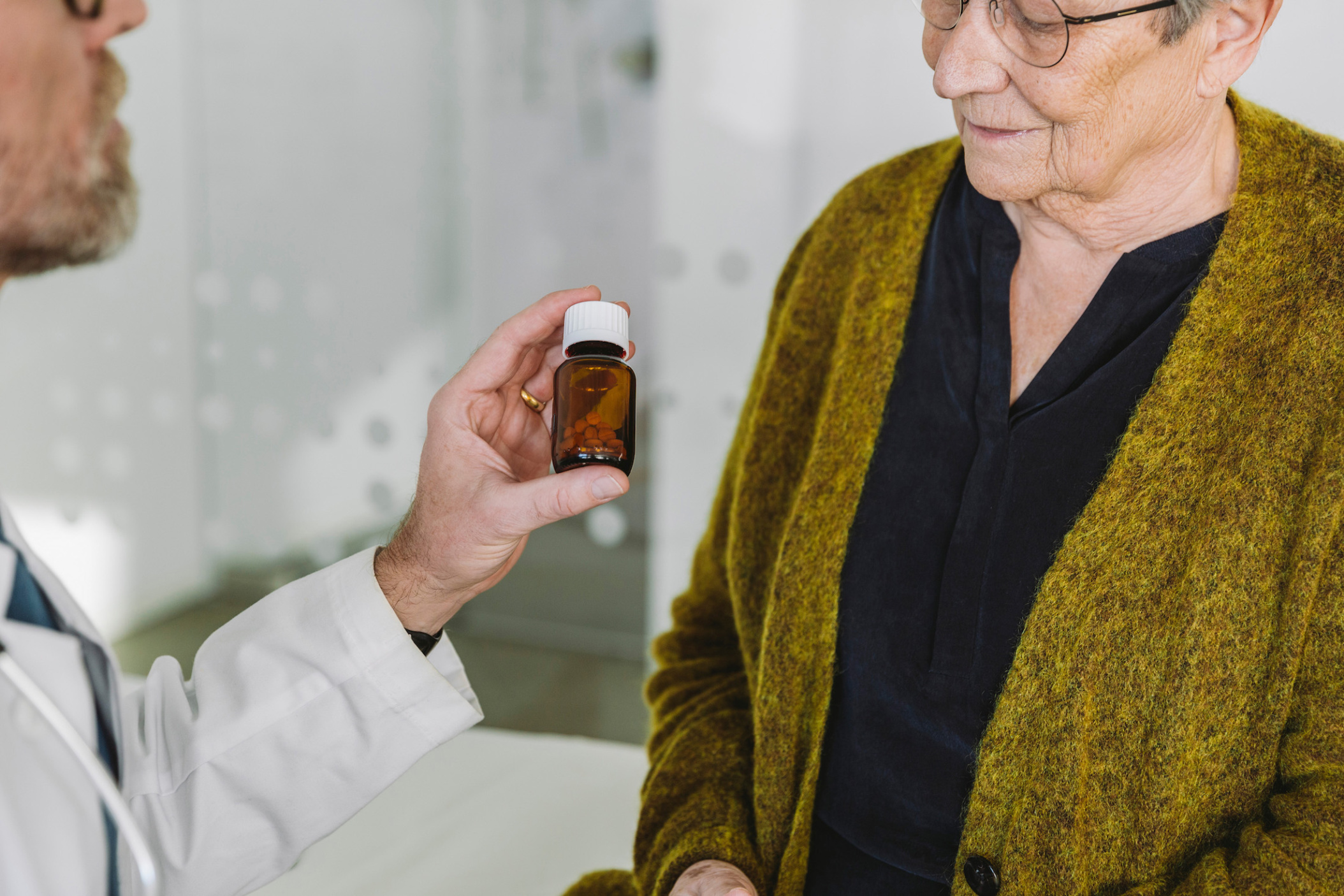 Doctor recommending pills in bottle to senior patient, Cologne, NRW, Germany