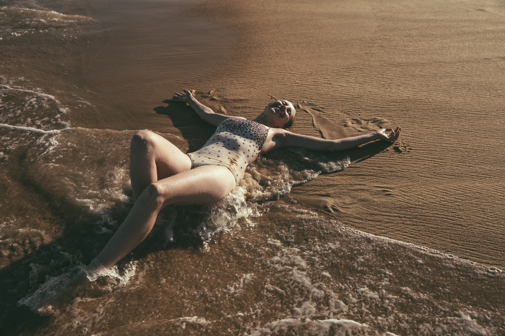 Woman laughing while maying in the wet sands and water of beach in Bahia, Brazil