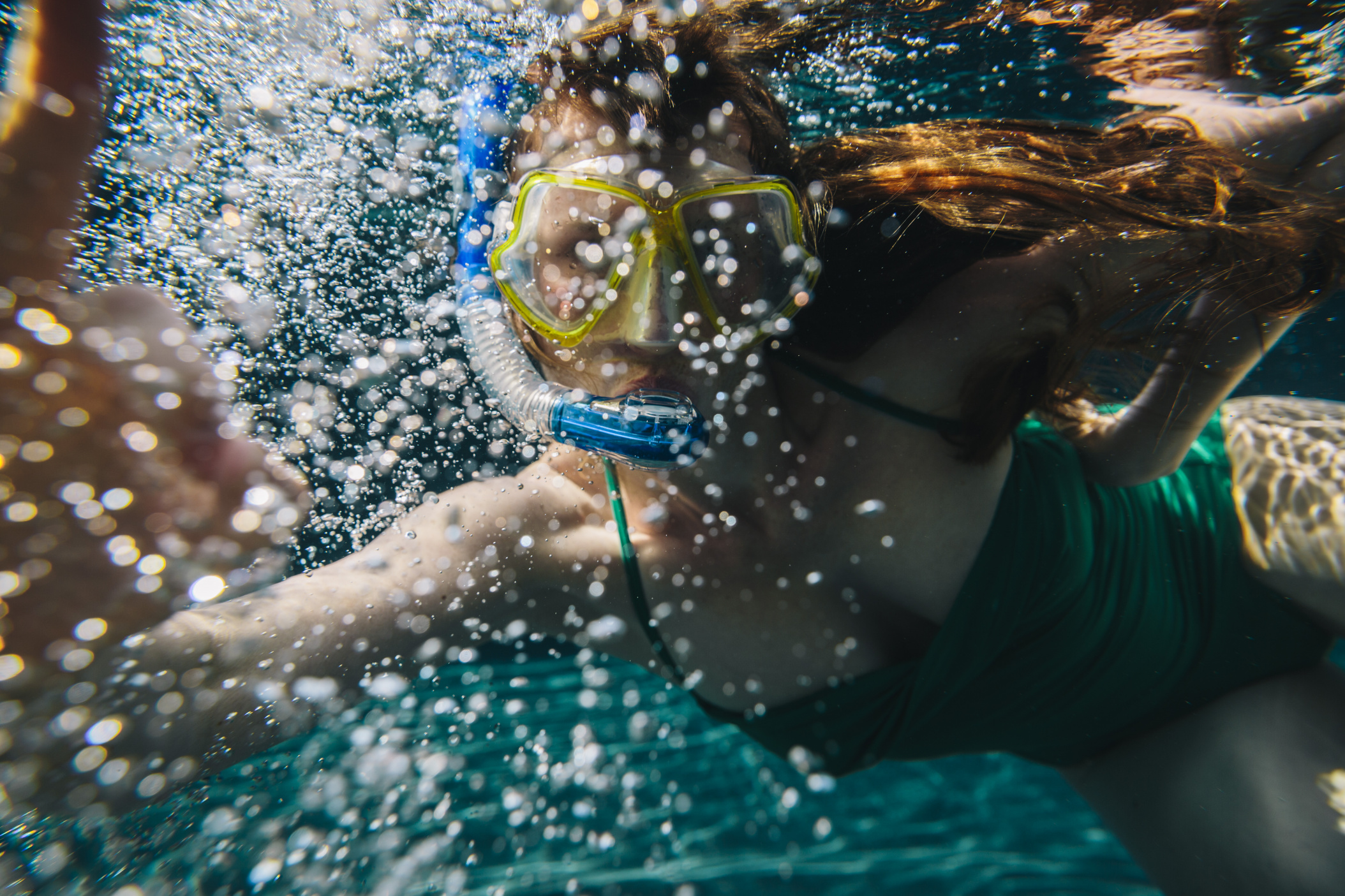 Woman with diving googles and air bubbles seen underwater in a swimming pool, Olhao, Algarve, Portugal