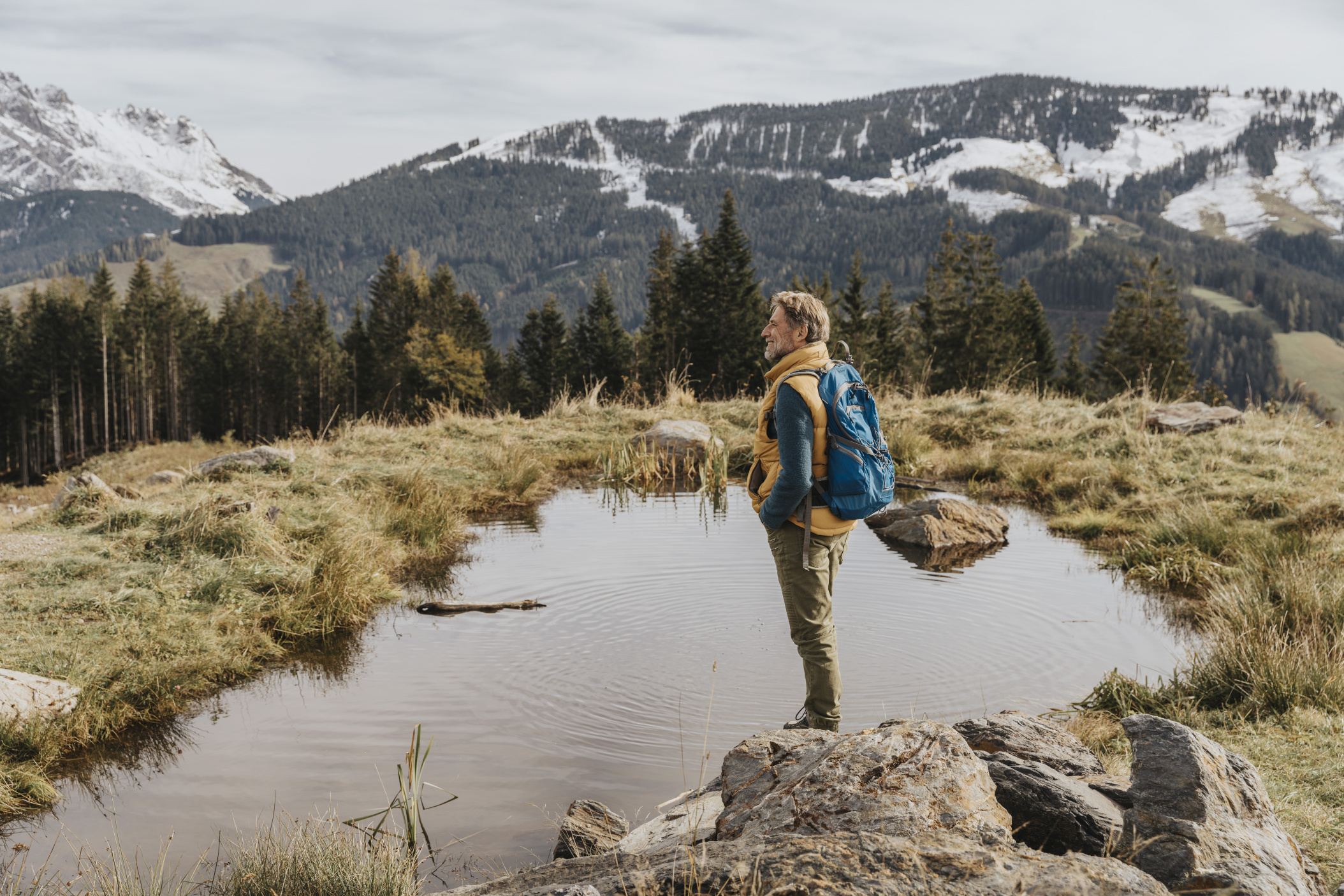 Mann steht an einem Teich und schaut auf die Berge im Salzburger Land, Oesterreich