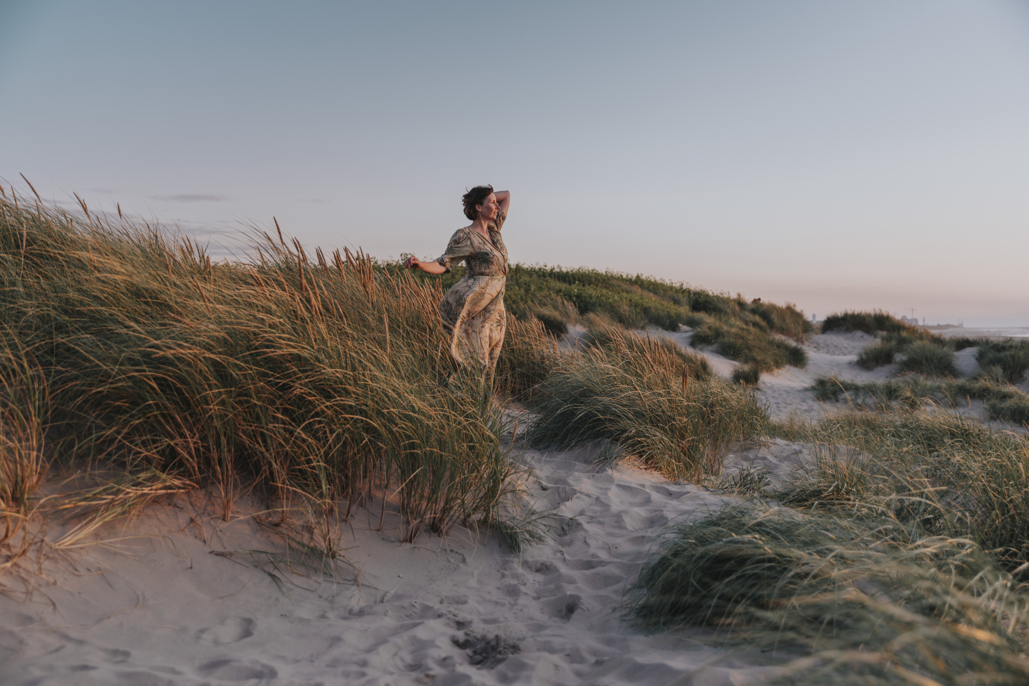 Woman enjoying the breeze between dunes during sunset, Nieuwpoort Beach, Belgium