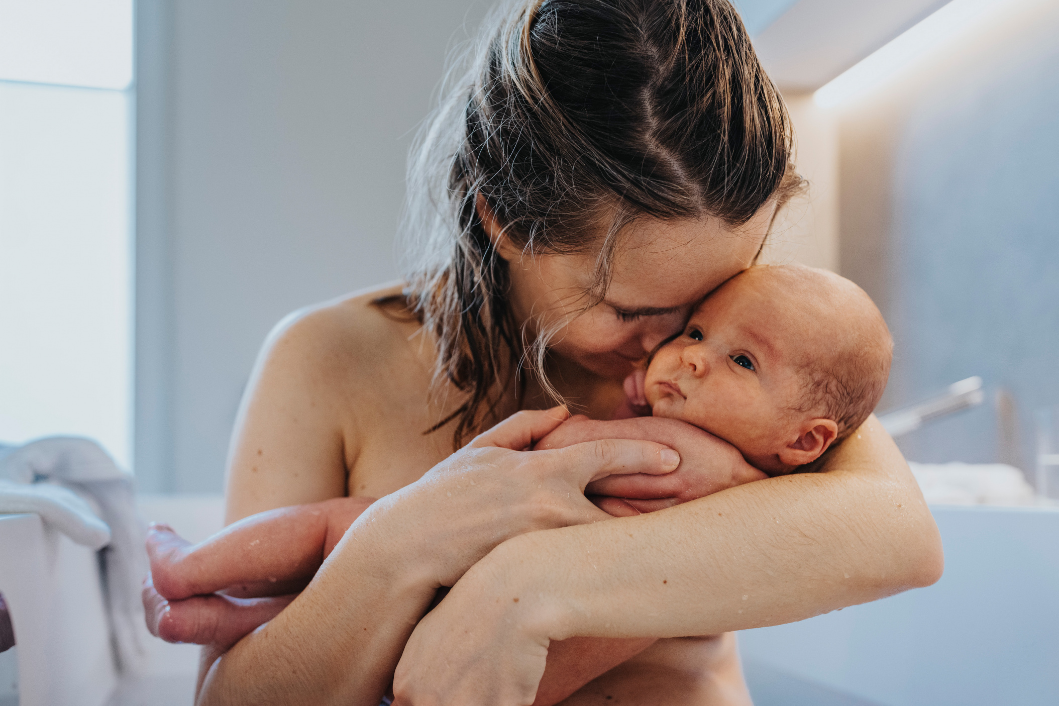Mother cuddling her newborn baby in bathtub, Cologne, NRW, Germany