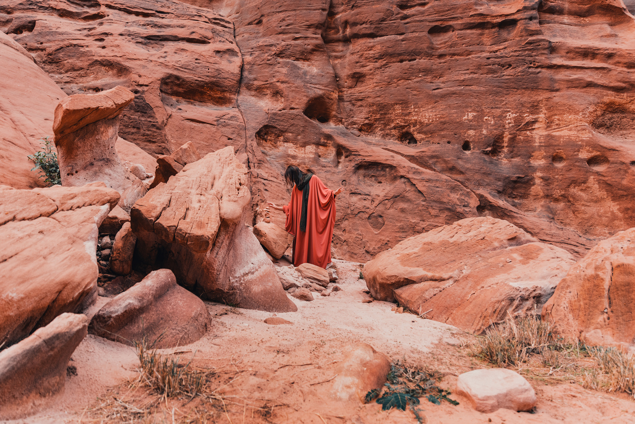 NEOM, SAUDI ARABIA – DECEMBER 9: Woman in Abaya dress and Hijab headscarf stacking sandstone rocks in Secret Garden of Hisma Desert on December 09, 2022, in NEOM, Saudi Arabia.