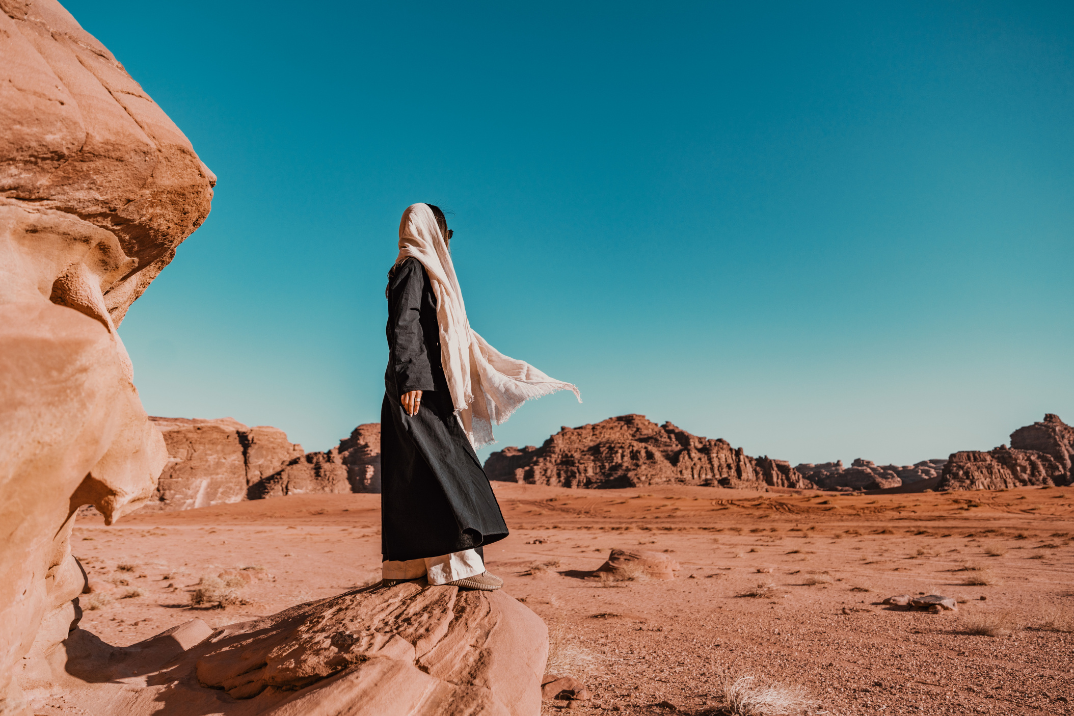 NEOM, SAUDI ARABIA – DECEMBER 9: Woman looking over of Hisma Desert from a large sandstone rock on December 09, 2022, in NEOM, Saudi Arabia.