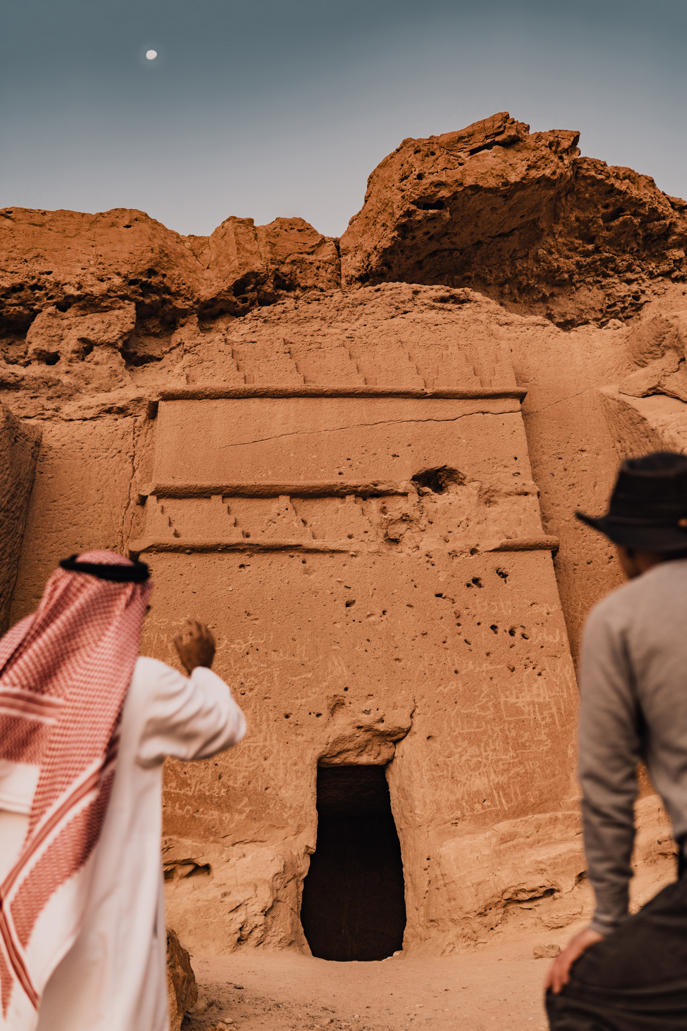 NEOM, SAUDI ARABIA – December 13: Saudi guide and explorer looking at Magha'er Shuaib ancient tomb facade during sunrise on December 13,2022, in NEOM, Saudi Arabia.