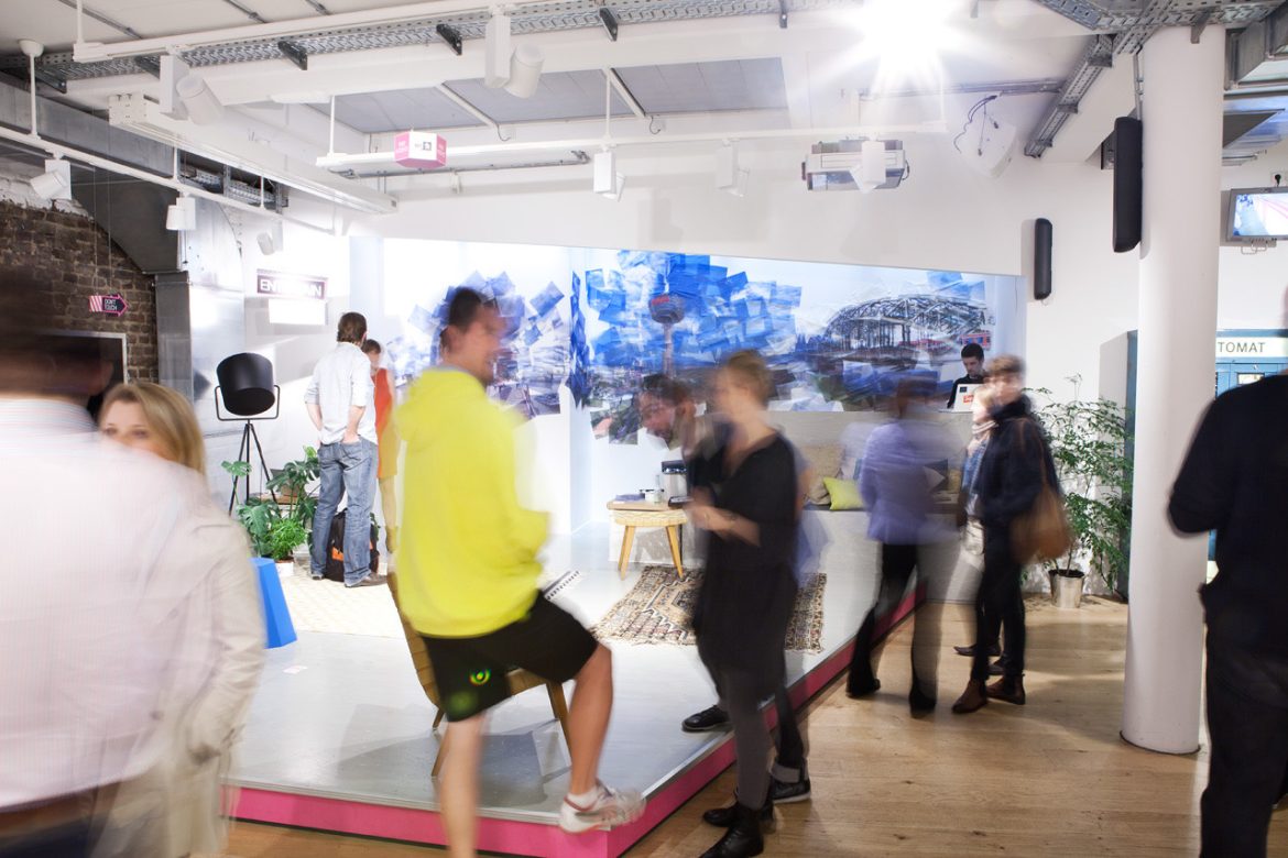 Busy modern exhibition space with people milling around displays by Mareen Fischinger