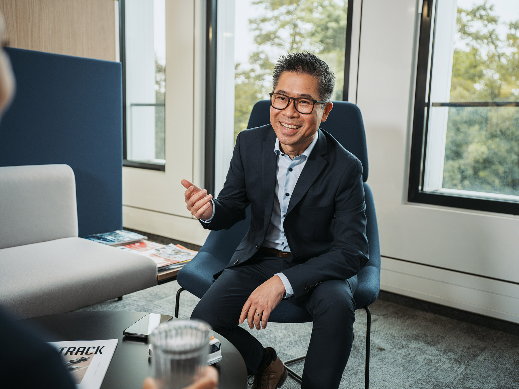 Lächelnder Geschäftsmann mit Brille im modernen Bürogespräch