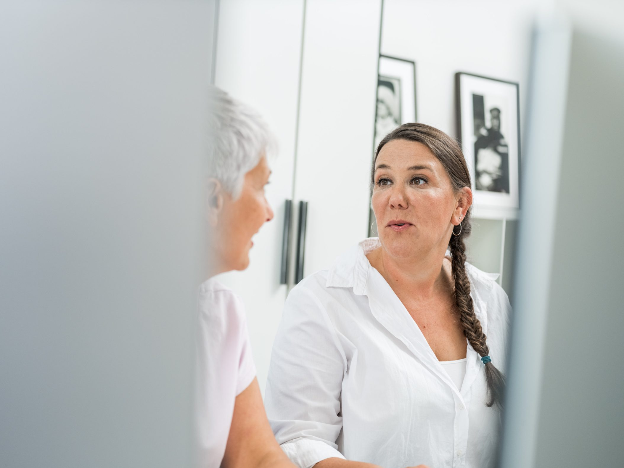 Two women in conversation in a bright white room by Mareen Fischinger