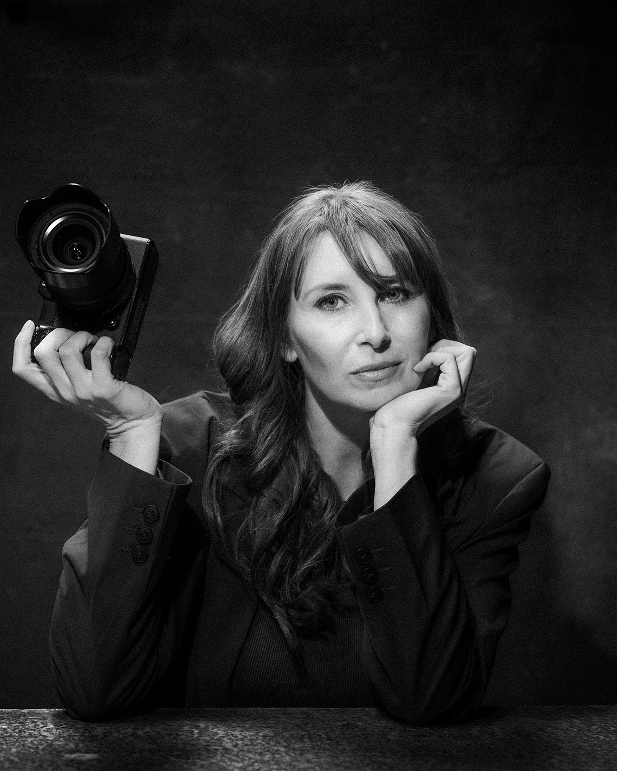 Woman photographer holding camera in black and white portrait