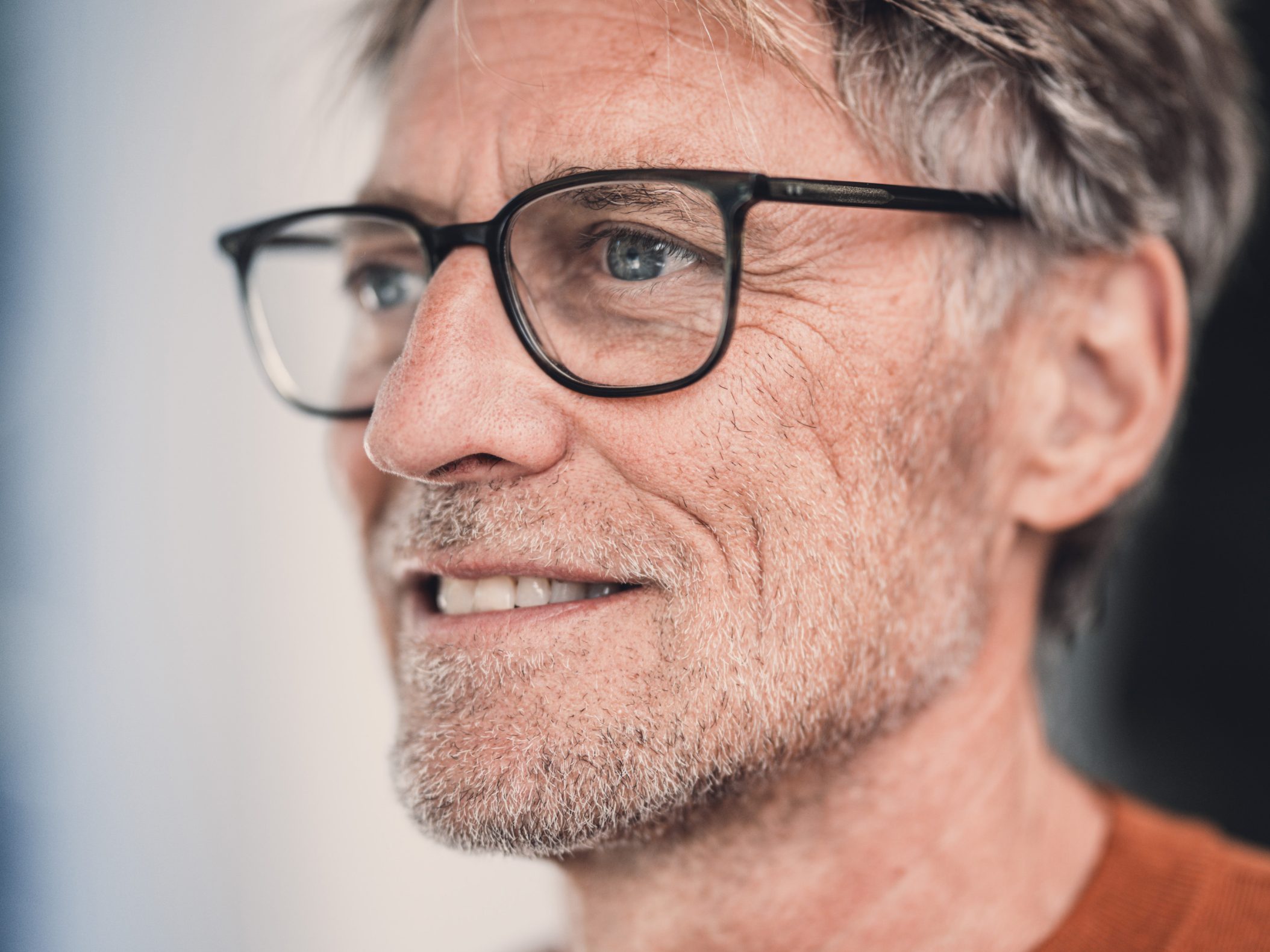 Älterer Mann mit Brille und grauem Haar lächelt