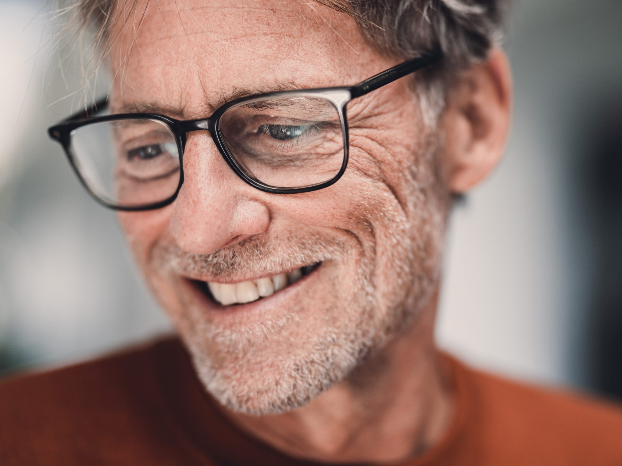 Lächelnder älterer Mann mit Brille und grauem Bart