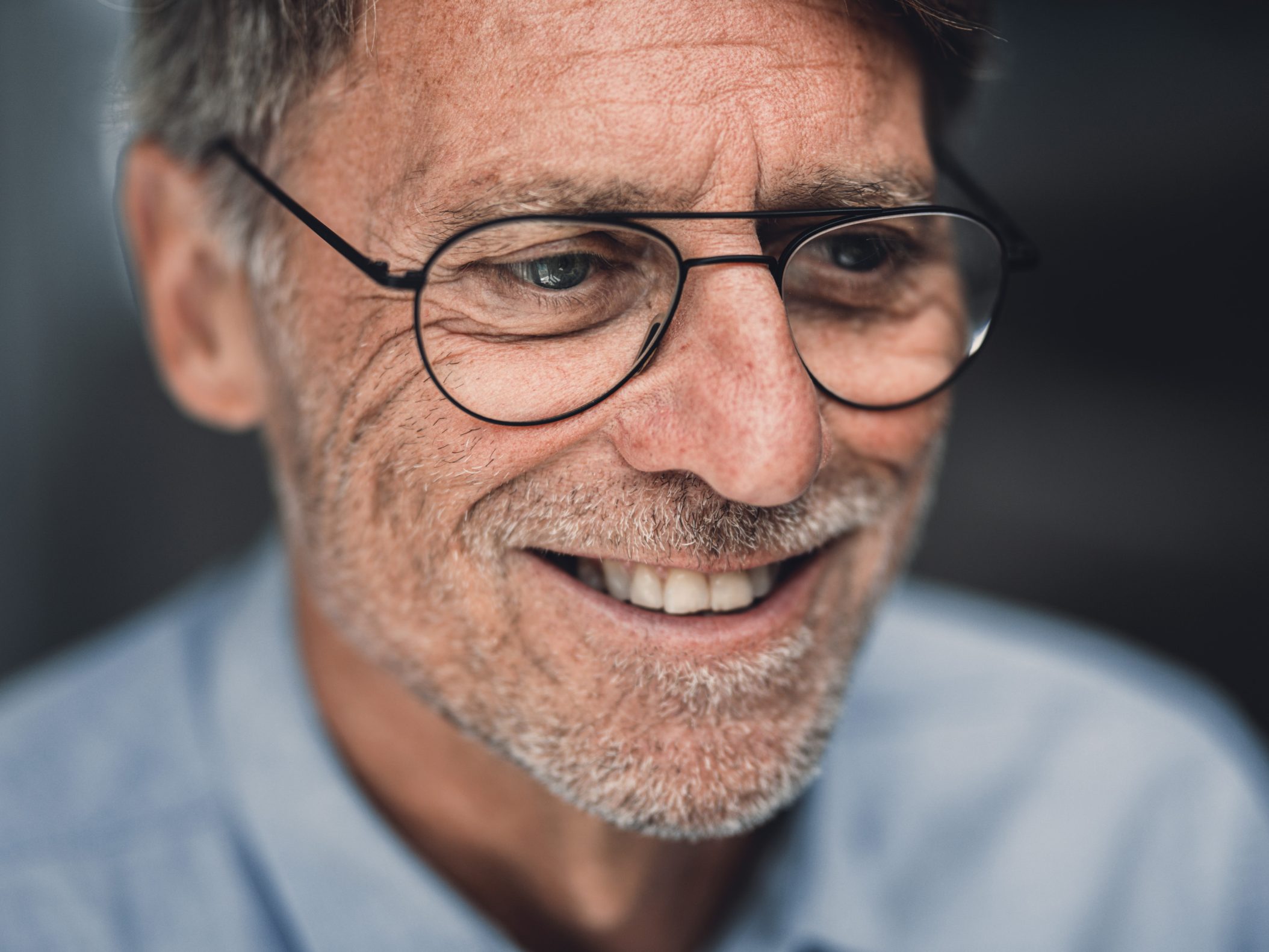 Lächelnder älterer Mann mit Brille und grauem Bart